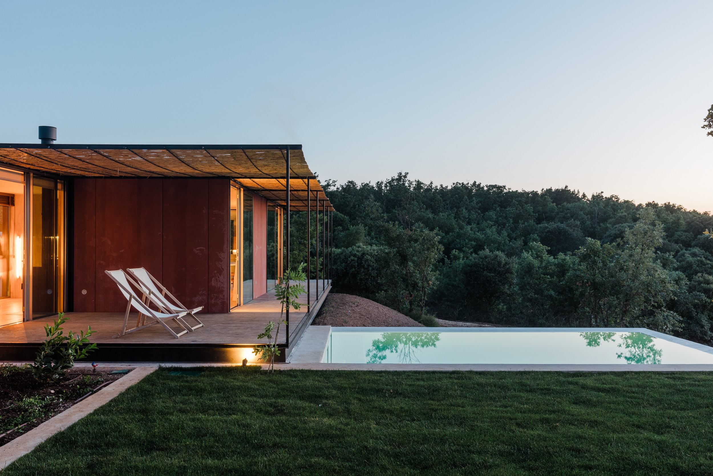 Casa modular Tini M de 36 m² con terraza de madera, tumbonas y piscina al atardecer frente al bosque