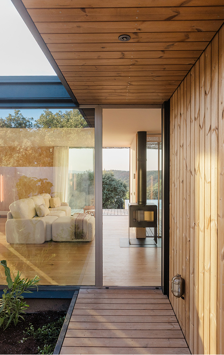 Acceso a la casa modular con fachada de madera termotratada y pasarela de tarima