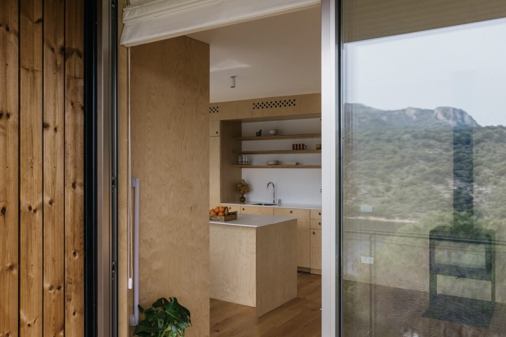 Cocina de madera clara de la casa modular Tini M vista desde el porche, con la sierra al fondo